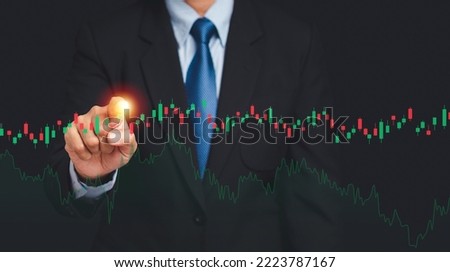 Midsection of a businessman in a suit pointing to graph stock on a virtual screen while standing on a black background. Close-up photo. Business, stock, and finance concept
