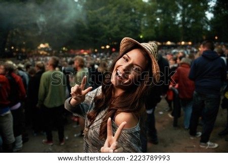 Its all about the vibe. A pretty young woman showing a peace sign at an outdoor music festival. Royalty-Free Stock Photo #2223789993