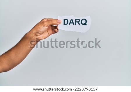 Hand of caucasian man holding paper with darq word over isolated white background