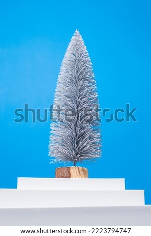 Christmas tree on a white podium on a blue background. 