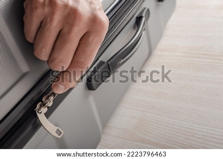 Closeup photo of male hand zipping travel suitcase for vacation