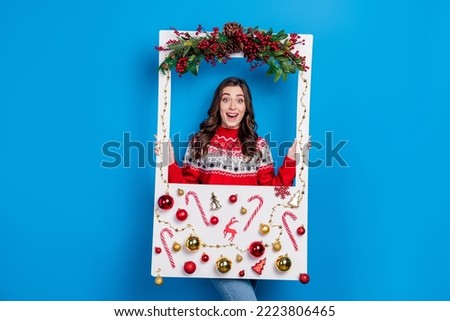 Photo of cheerful pretty lady wear ugly sweater hold frame decorated pine spruce cone sweets caramel cane isolated on blue color background