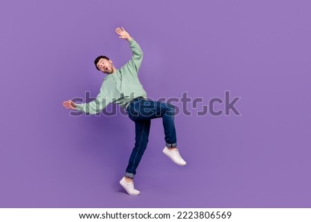 Full body side length photo of young excited stressed man funny unexpected dangerous falling down tiptoe empty space ad isolated on violet color background
