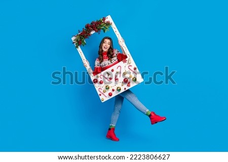 Full length photo of positive overjoyed cute lady hold frame decorated ball pine spruce cone sweet candy isolated on blue color background