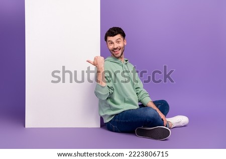 Full size photo of handsome young man sit floor point vertical menu poster wear trendy gray look isolated on violet color background