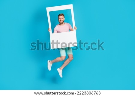 Full body photo of attractive young man hold social media photo frame jumping wear trendy pink clothes isolated on cyan color background