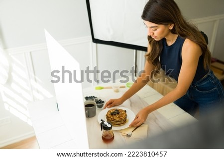 Woman photographer taking professional photos of pancakes and doing food styling during a shooting at the studio