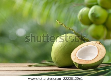 Coconut with cut in half on wooden table.