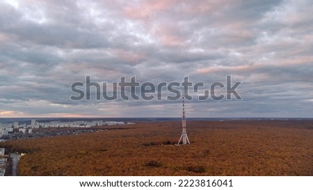 Aerial view on telecommunication tower in autumn forest near residential district with scenic cloudy sky. Kharkiv city, Ukraine