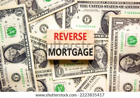 Reverse mortgage symbol. Concept words Reverse mortgage on wooden blocks. Beautiful background from dollar bills. Business and reverse mortgage concept. Copy space. Royalty-Free Stock Photo #2223835417