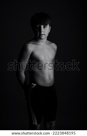 Boy looks attentive posing shirtless, black and white studio photography