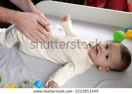 Masseur massaging the tummy of the baby during colic. Mother massaging infant belly, kid laughing.