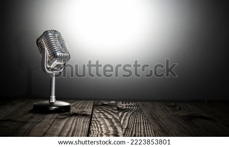 Vintage microphone on dark table and bright background - vlog and content creation concept.
