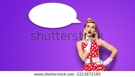 Studio portrait image of thinking woman in red pin up dress. Blond pinup thougthfull girl on violet purple background. White empty blank speech sign bubble, having idea. Mockup, ready for your design.