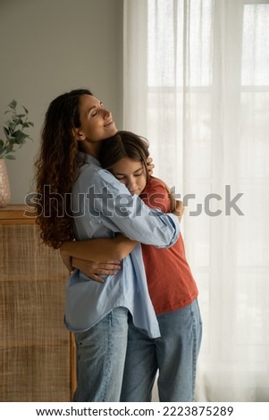 Young loving mother hugging her teenage daughter, mom demonstrating unconditional love for child, mommy cuddling supporting upset teen girl while spending time together at home. Mother-daughter bond  Royalty-Free Stock Photo #2223875289