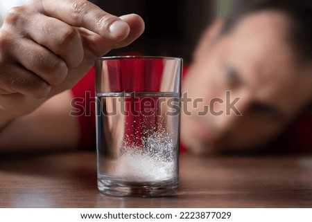 Man throwing a hangover pill into a glass of water. Effervescent tablet in water with bubbles.