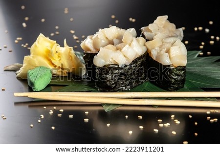 Set of sushi and rolls decorated with wasabi and ginger isolated on black background