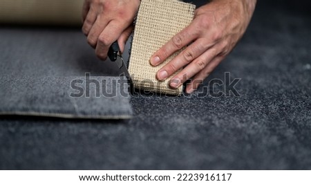 Handyman cutting a new carpet with a carpet cutter..	 Royalty-Free Stock Photo #2223916117