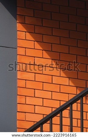 Light and shadow on surface of brick and gray concrete wall with steel balustrade on balcony of vintage house in low angle view and vertical frame