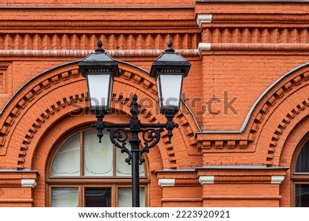 Decorative street lights on the background of a brick wall of an old building with arched windows