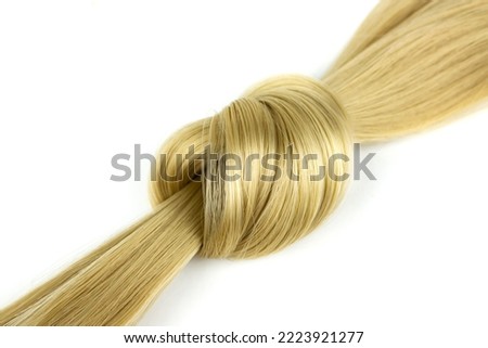 Blonde hair lock tied in knot. Strand of honey blonde hair on white background, top view. Blond wavy hair on white background Royalty-Free Stock Photo #2223921277