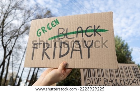 Hand holding sign Green Black Friday, word Black crossed out. Protester with placard at zero waste protest rally. Ecology environmental issues, demonstration against Black Friday Sale, overproduction.