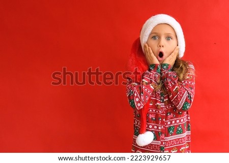 Excited suprise wow open mouth kid girl wearing Christmas red Santa hat green pajamas costume isolated studio background. Christmas sale and discount. Shopping. Banner, copy space for text, mock up