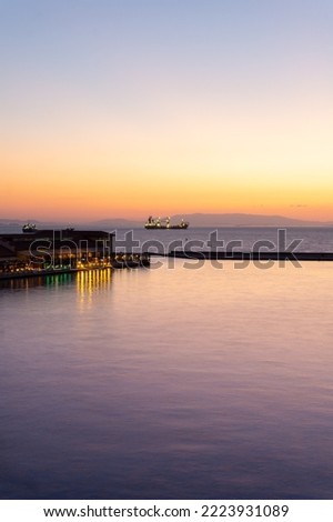 Landscape at sunset of the port of Izmir in Turkey with the silhouette of ships sailing and the mountains in the background in vertical format.