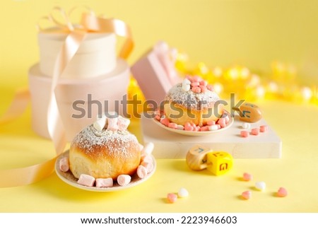 Hanukkah holiday card with sweet doughnuts sufganiyot (traditional donuts), gifts and bokeh lights. Selective focus