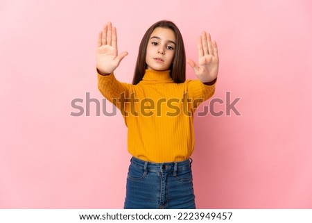 Little girl isolated on pink background making stop gesture and disappointed
