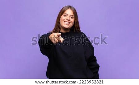 young blonde woman pointing at camera with a satisfied, confident, friendly smile, choosing you