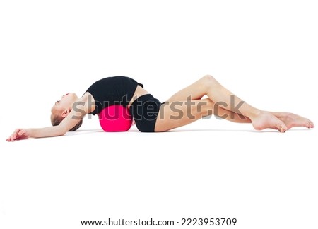 Young beautiful gymnast beautifully arched around a red ball Isolated on white background