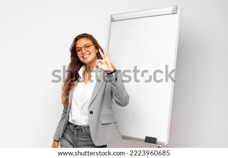young businesswoman feeling happy, relaxed and satisfied, showing approval with okay gesture, smiling Royalty-Free Stock Photo #2223960685