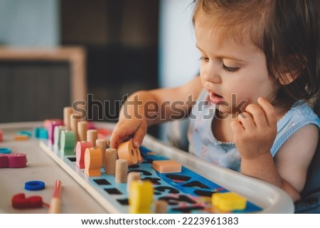 Baby girl playing with different color wooden elements making tasks for education and brain exercise. Counting math play game. Wooden toys.