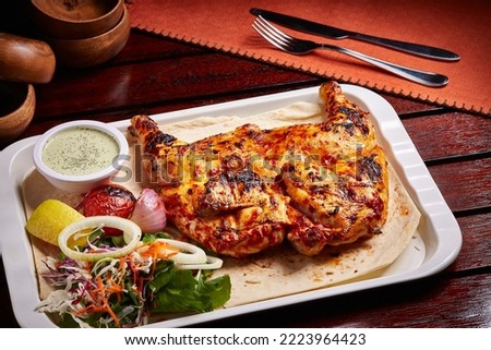 Charcoal Grilled Chicken with bread, salad, lemon and raita served in dish isolated on table side view of middle east food Royalty-Free Stock Photo #2223964423