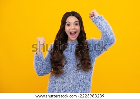 Amazed teen girl. Excited expression, cheerful and glad. Teenager child doing winner gesture celebrate clenching, say yes isolated on yellow background, studio portrait. Excited teen girl.