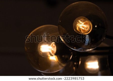 Tungsten lamps glow in round glass lampshades, close-up photo with selective soft focus Royalty-Free Stock Photo #2223985753