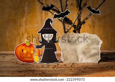 Little witch with halloween pumpkin and blank paper.