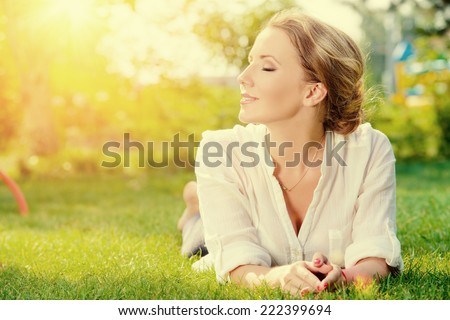 Beautiful smiling woman lying on a grass outdoor. She is absolutely happy.  Royalty-Free Stock Photo #222399694