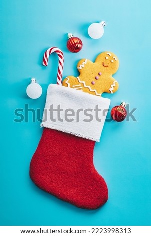 Christmas stocking with gingerbread man, candy cane,  red and white baubles on blue background