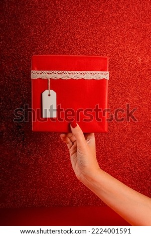 Frontal view of red gift box with white tag against red backgrou