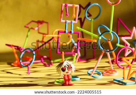 multi-colored plastic constructor in the form of various figures  and a cartoon figure made of air plasticine on a bright background with hard shadows from sunlight selective focus.