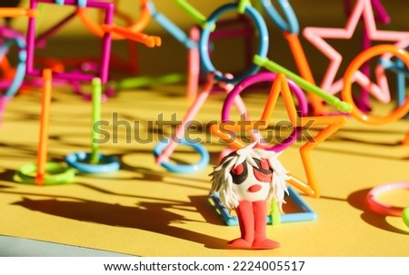multi-colored plastic constructor in the form of various figures  and a cartoon figure made of air plasticine on a bright background with hard shadows from sunlight selective focus.