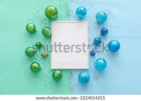 Composition with blank picture frame and Christmas balls on color background