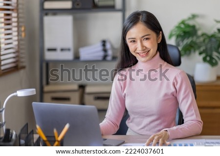 Asian Businesswoman Using laptop computer and working at office with calculator document on desk, doing planning analyzing the financial report, business plan investment, finance analysis concept.
