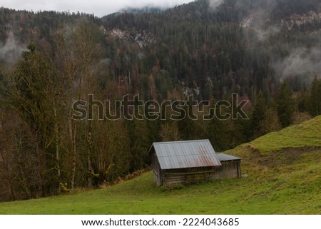 Small farm hay cabin in the Alpine Oberbayern region of Germany. Hill covered with trees with colourful autumn foliage in the background Royalty-Free Stock Photo #2224043685