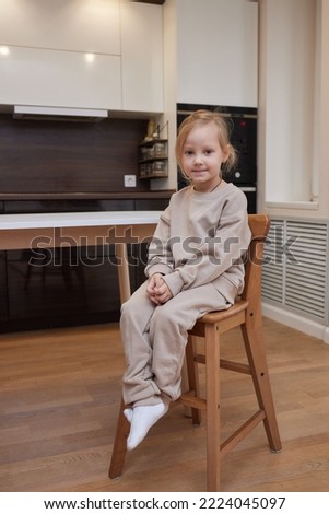 girl in warm overall and woolen socks sitting on soft blanket.
