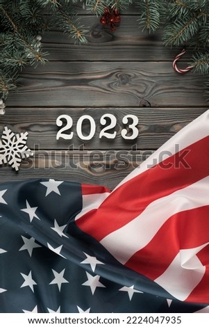 Vertical dark wooden wallpaper with American flag 2023 and Christmas toy frame decoration. Happy new year and merry xmas. Green card emigration and elections. Copy space, flat lay, mockup, template