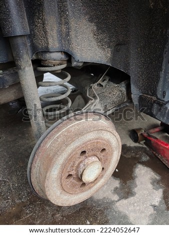 Rear rusty car disc with removed wheel, brake pad and car spring close-up