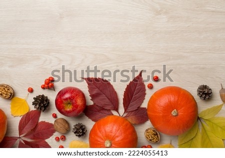 Festive autumn flat lay with pumpkins, berries and leaves on wooden background, top view.